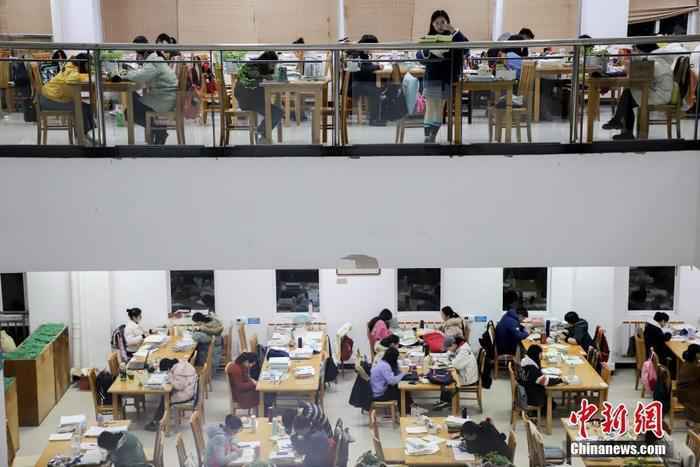 资料图:贵州民族大学逸夫图书馆内,考研学生正在看书复习。 中新社记者 瞿宏伦 摄 扩招18.9万!考研族“上岸”会更容易吗?